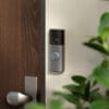 Een Ring Video Doorbell gemonteerd op een muur naast een houten voordeur