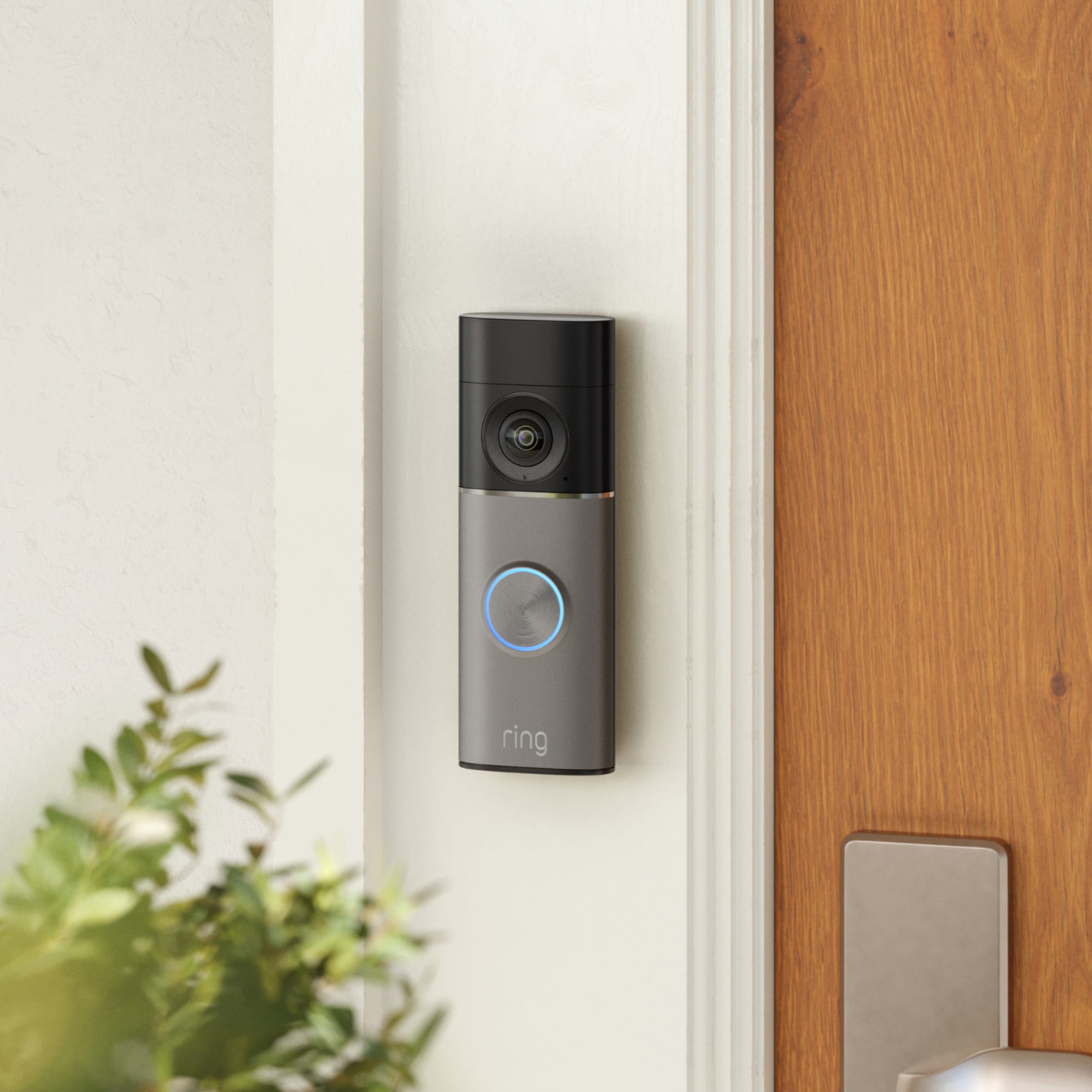 Ring Video Doorbell gemonteerd op een wit deurkozijn naast een houten deur