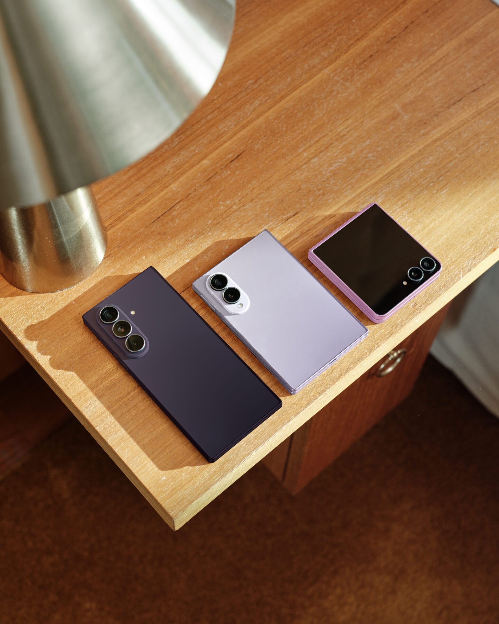 Drie Samsung Galaxy Z-smartphones (Fold8 Ultra, Fold8 en Flip8) naast elkaar op een houten tafel