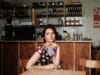 Een vrouw zit aan een tafel in een café en houdt een paarse Samsung Galaxy Z Fold8 vast