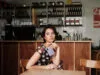 Een vrouw zit aan een tafel in een café en houdt een paarse Samsung Galaxy Z Fold8 vast