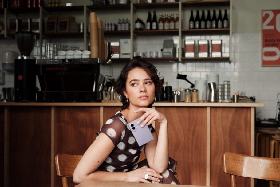 Een vrouw zit aan een tafel in een café en houdt een paarse Samsung Galaxy Z Fold8 vast