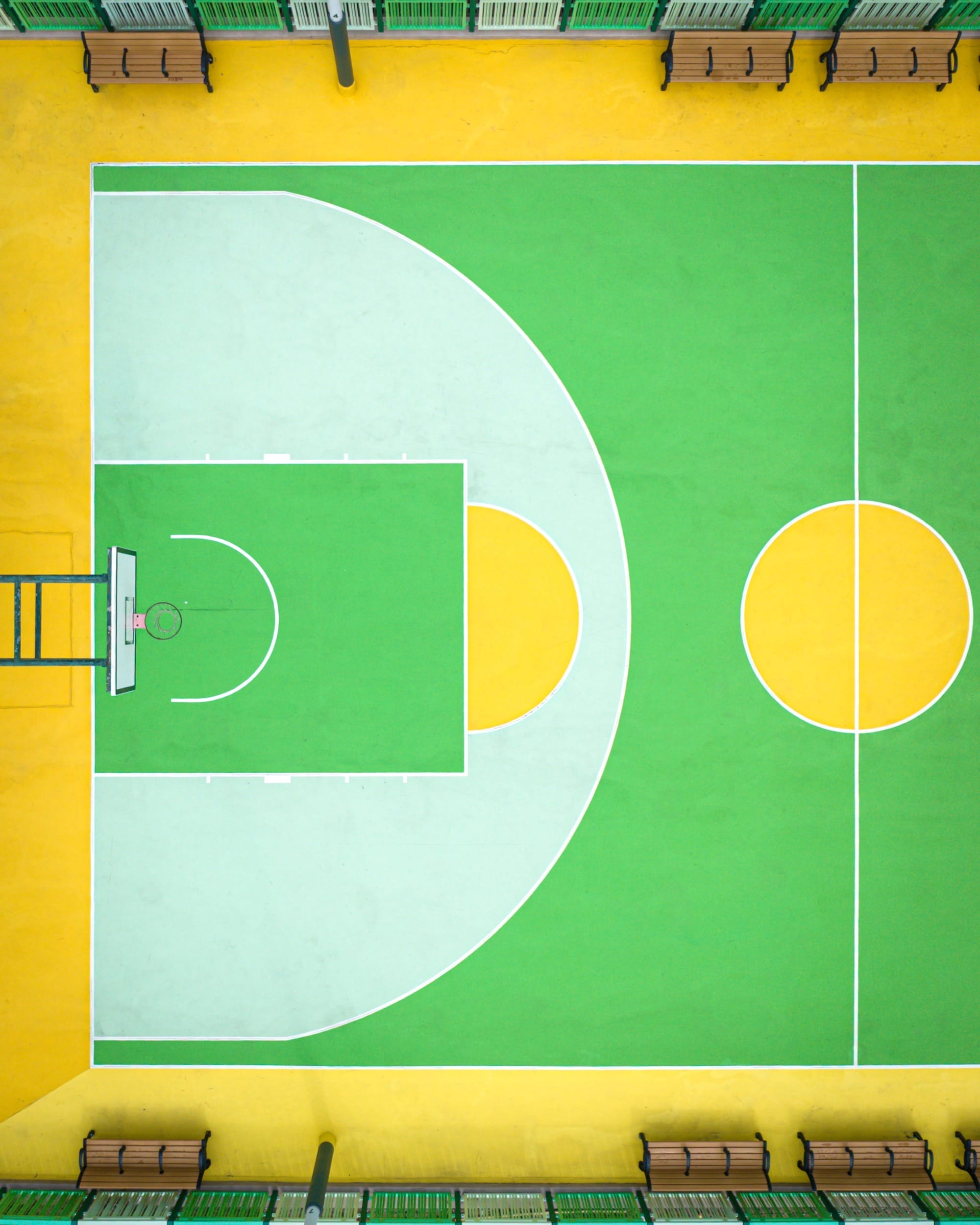 Bovenaanzicht van een basketbalveld in Hong Kong met een geometrisch patroon in felle tinten groen en geel