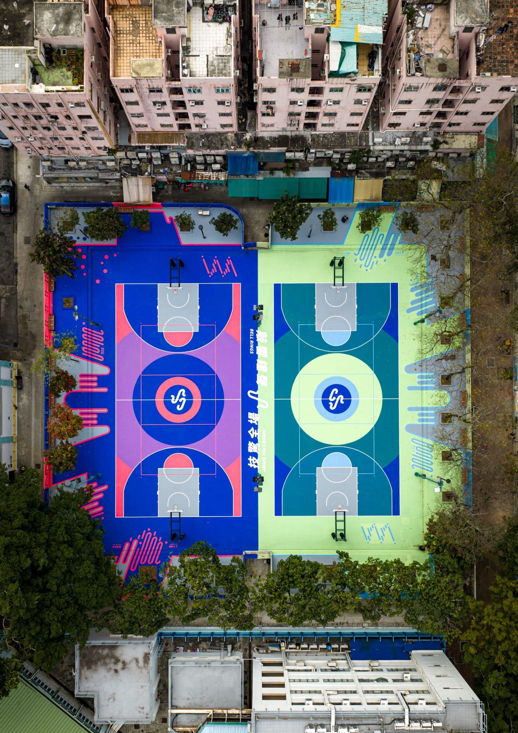 Bovenaanzicht van een basketbalveld in Hong Kong met felle blauwe, paarse en groene geometrische patronen tussen gebouwen