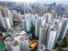 Luchtfoto van een dichtbebouwde wijk in Hong Kong met hoge, lichtblauwe en witte woontorens en een kleurrijk sportveld