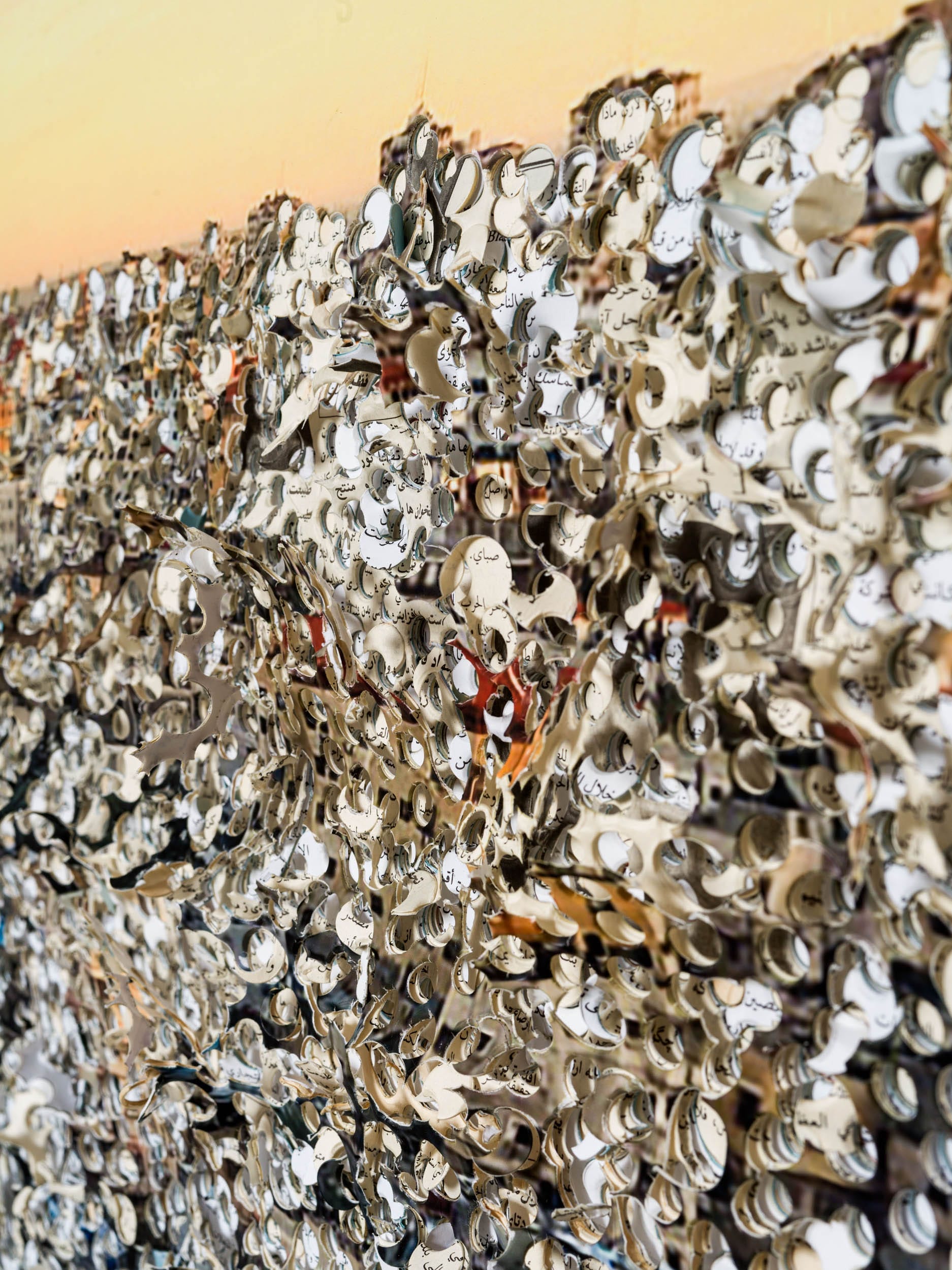 Een abstract kunstwerk bestaande uit een dichte collage van uitgesneden papierfragmenten met Arabische kalligrafie