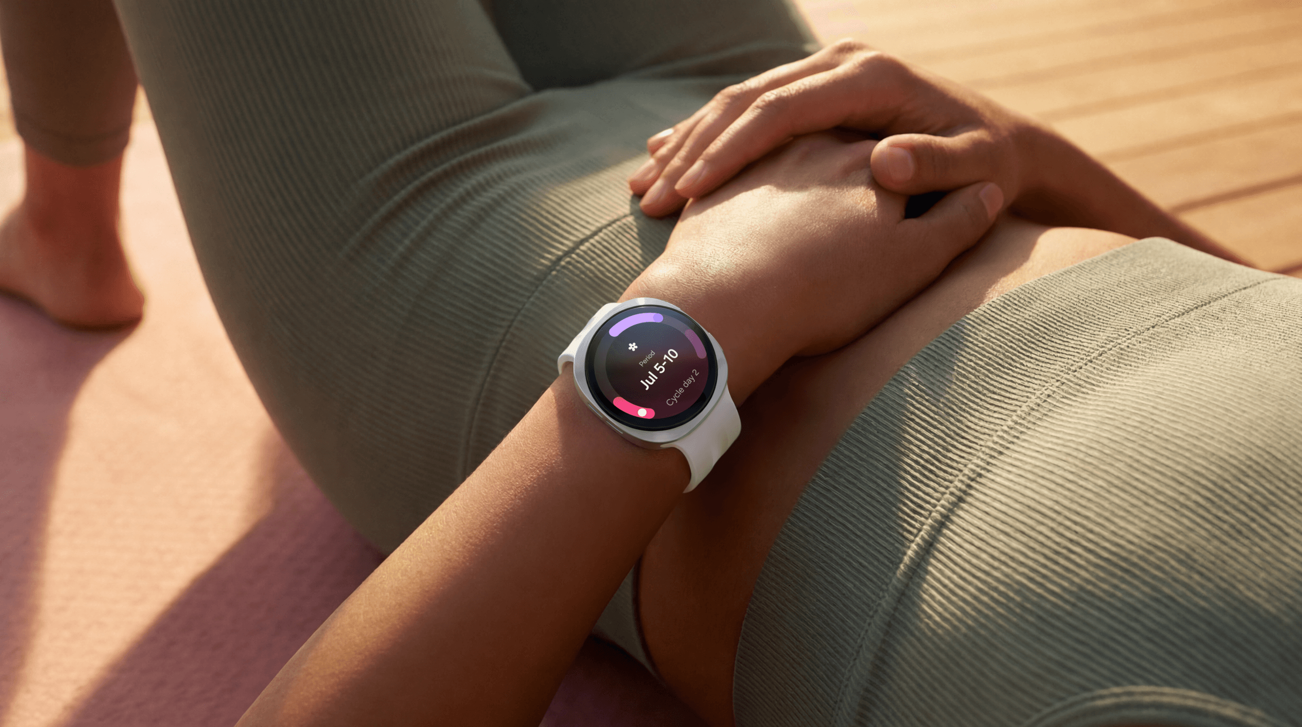 Een persoon ligt op een yogamat en draagt de Galaxy Watch9, die informatie over de menstruatiecyclus weergeeft