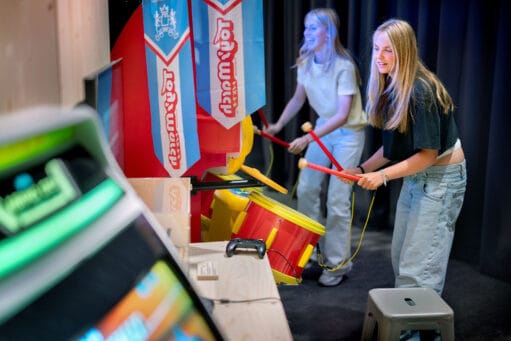 Twee lachende meiden spelen op een Taiko no Tatsujin arcade-drummachine