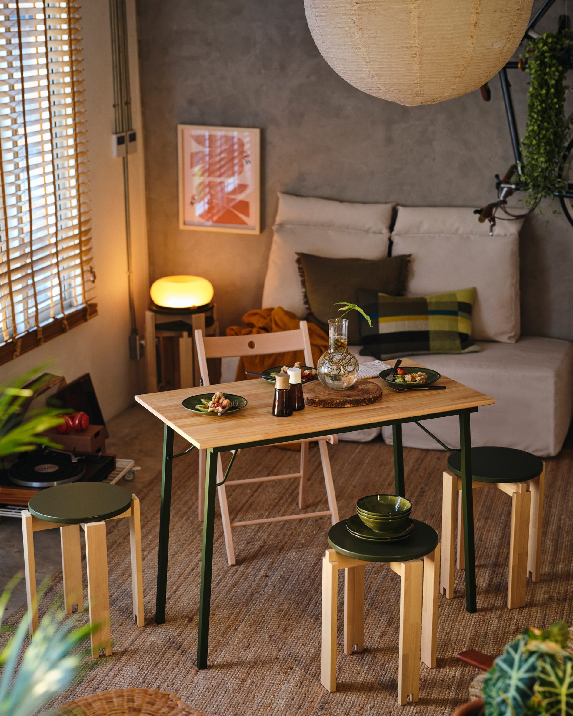 Houten tafel met groene poten en bijpassende krukjes uit de IKEA KOMPISHÄNG-collectie in een sfeervolle kamer