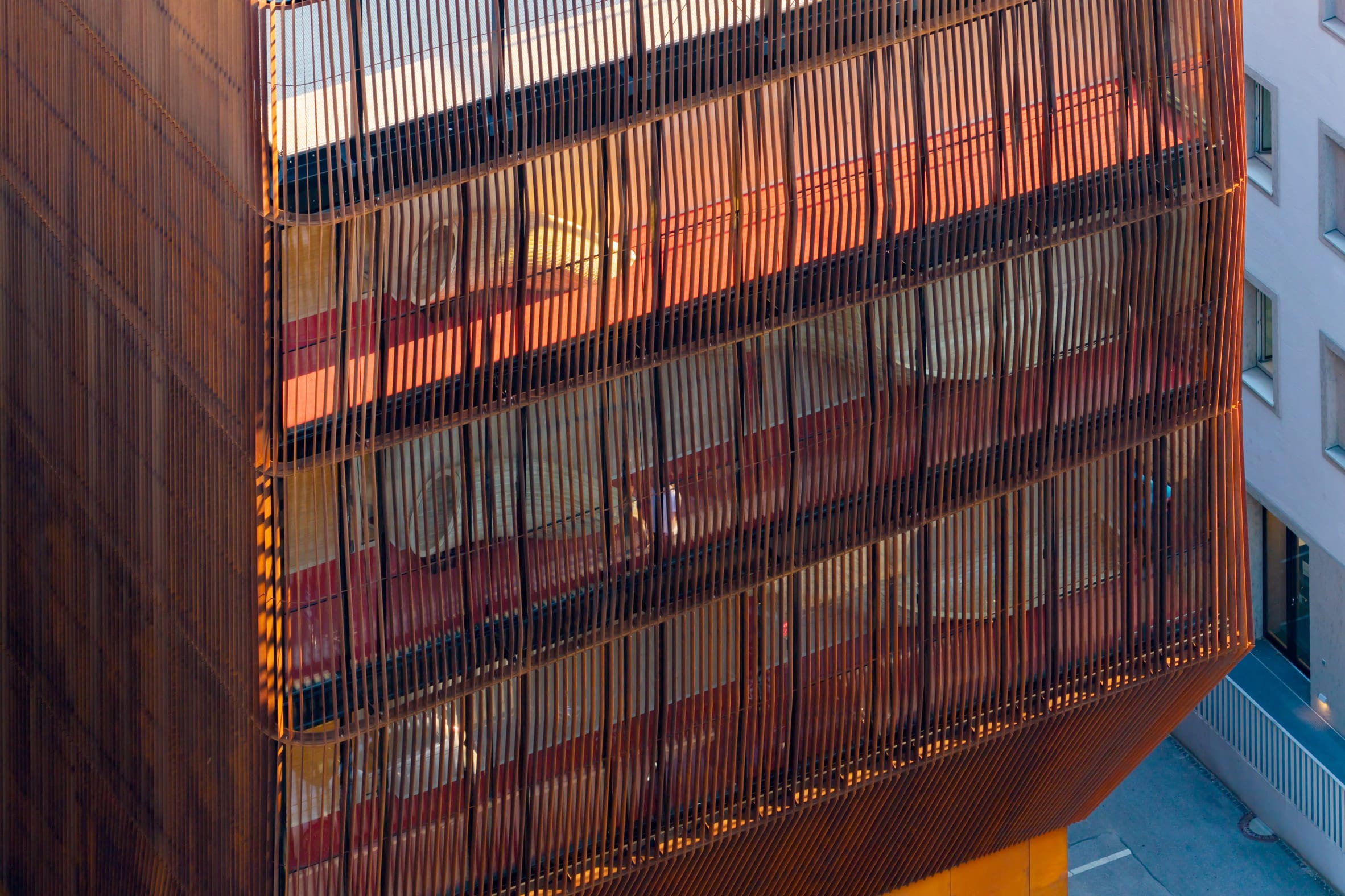 Modern gebouw met een gevel van verticale roestbruine lamellen die het zonlicht filteren