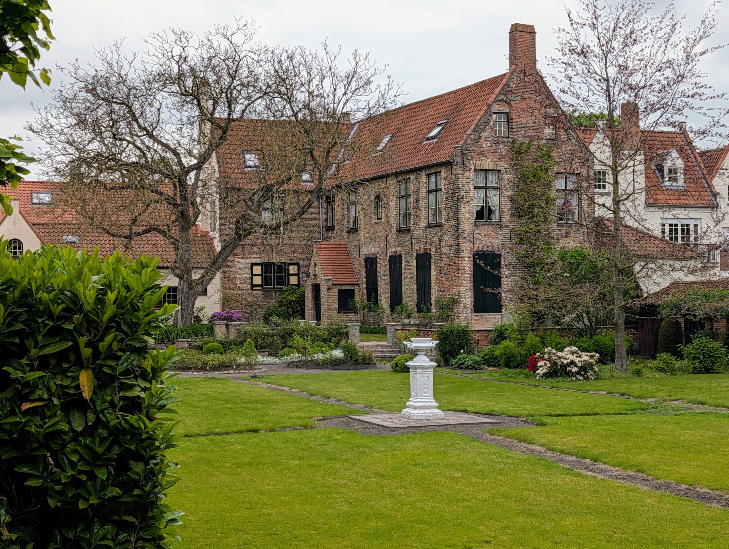 Historisch bakstenen gebouw met een rode dakpannen en een grote tuin met een wit ornament op het gazon