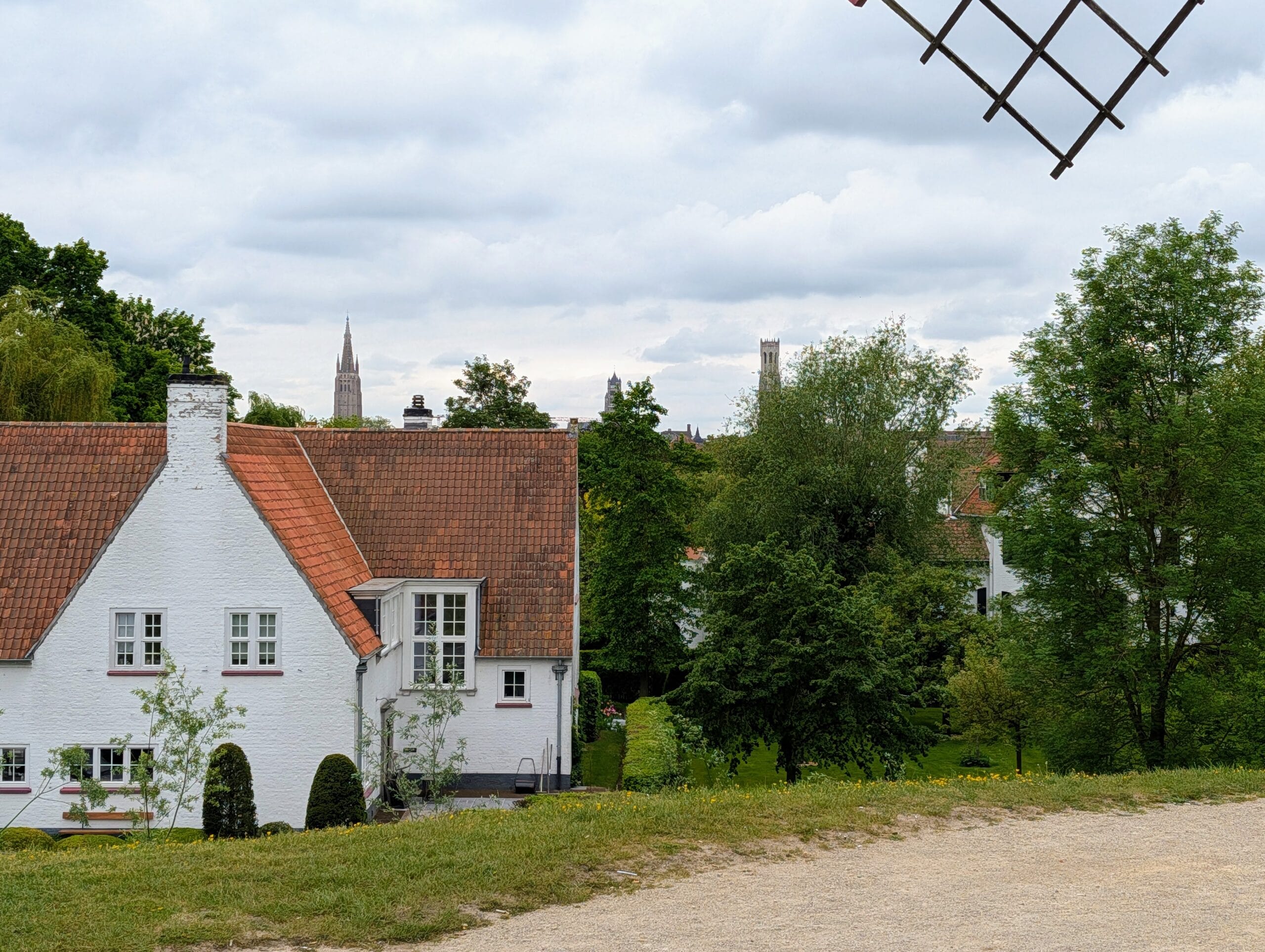 Uitzicht op witte huizen met rode daken in Brugge, met de Onze-Lieve-Vrouwekerk en het Belfort aan de horizon