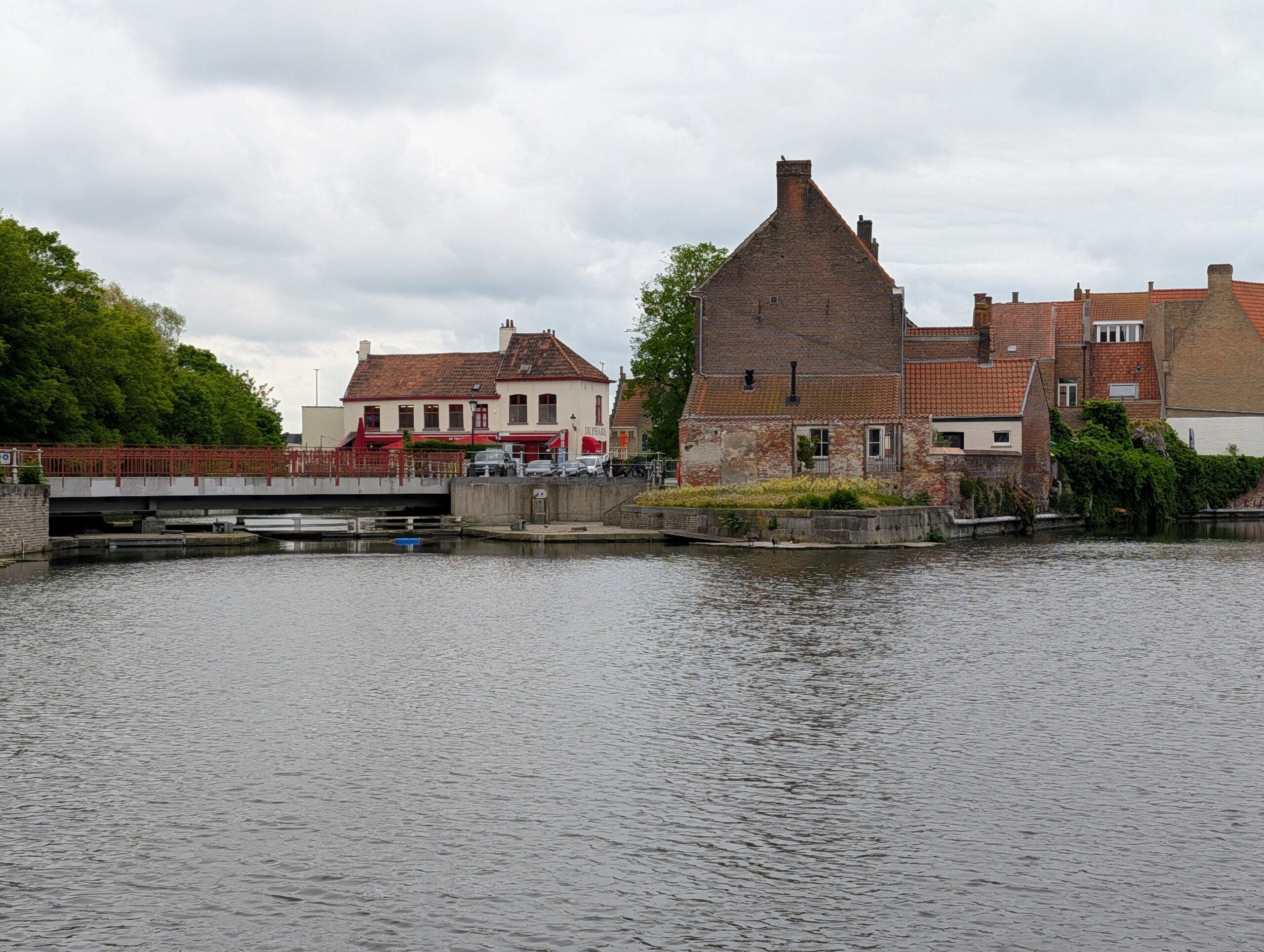 Zicht op historische bakstenen huizen en een brug aan de Ringvaart in de rustige Sint-Anna wijk van Brugge