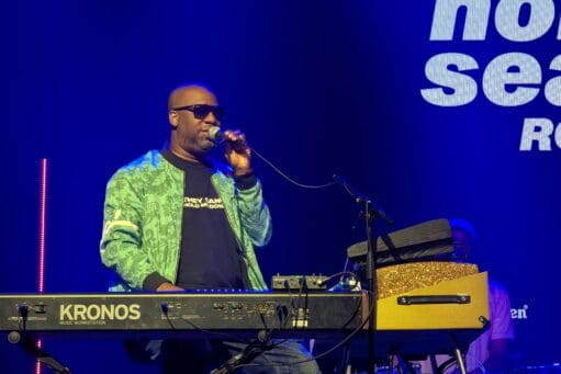 Robert Glasper zingt in een microfoon terwijl hij achter een Korg Kronos keyboard staat tijdens North Sea Jazz