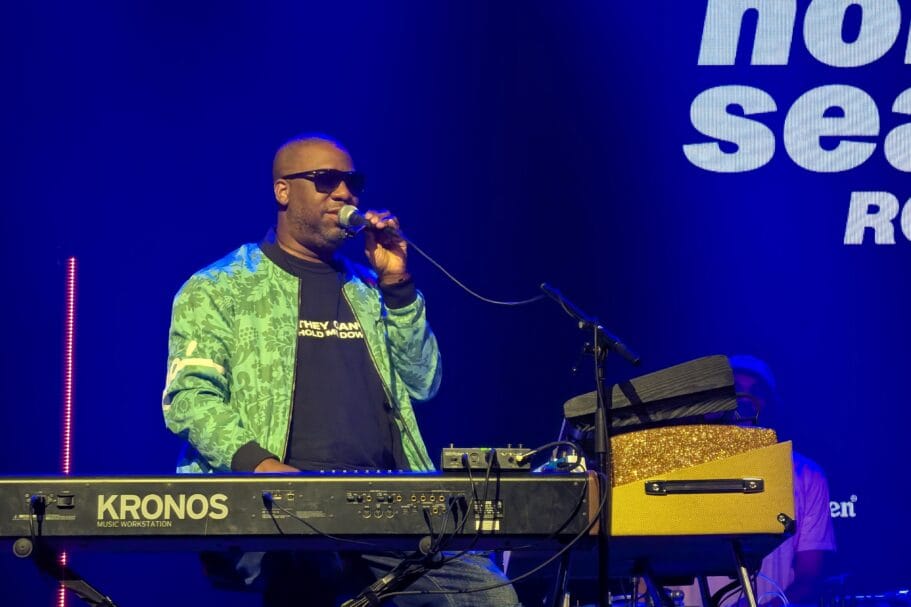 Robert Glasper zingt in een microfoon terwijl hij achter een Korg Kronos keyboard staat tijdens North Sea Jazz