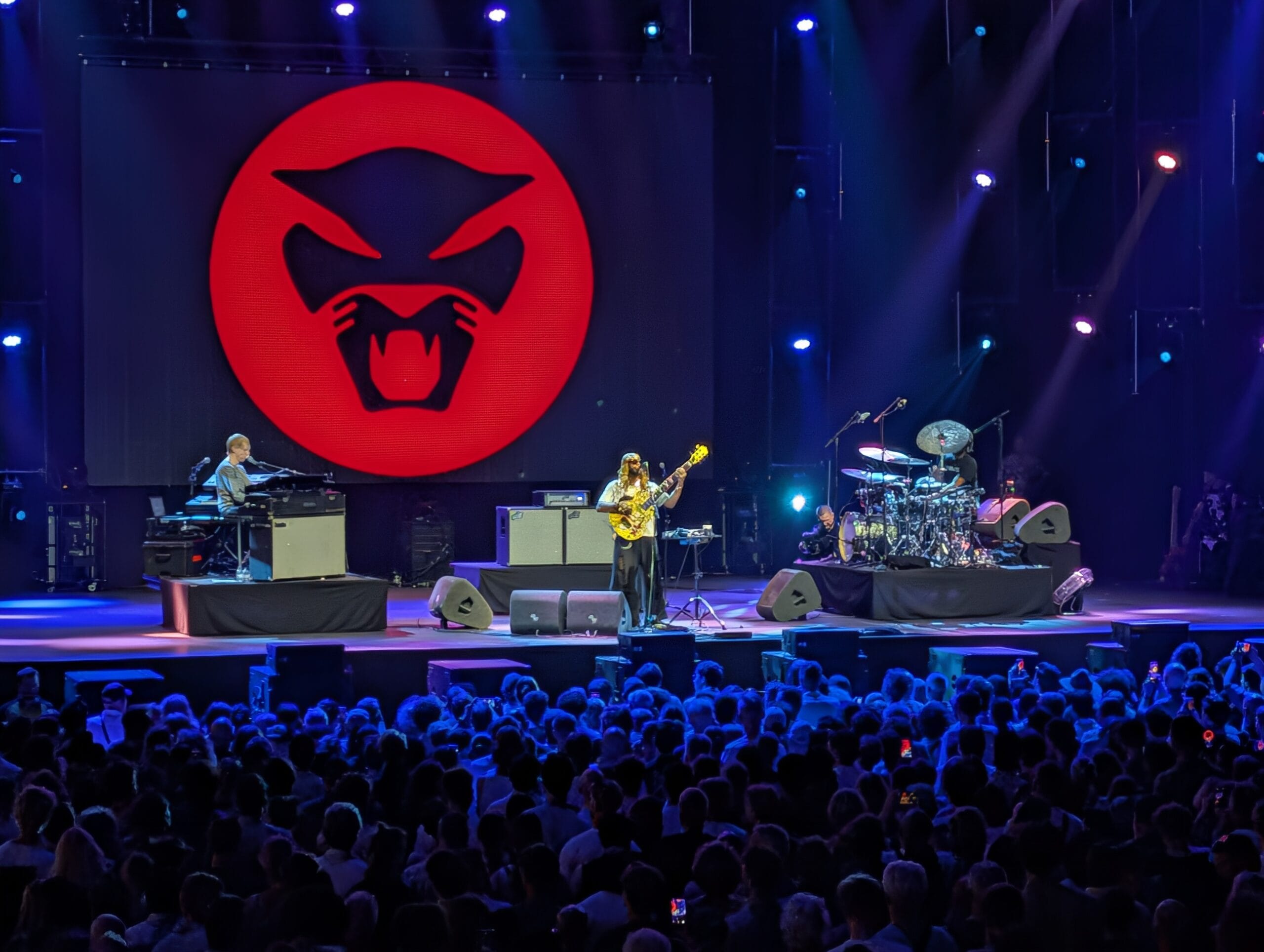 Thundercat treedt live op voor een groot publiek met een rood logo van een kat op de achtergrond