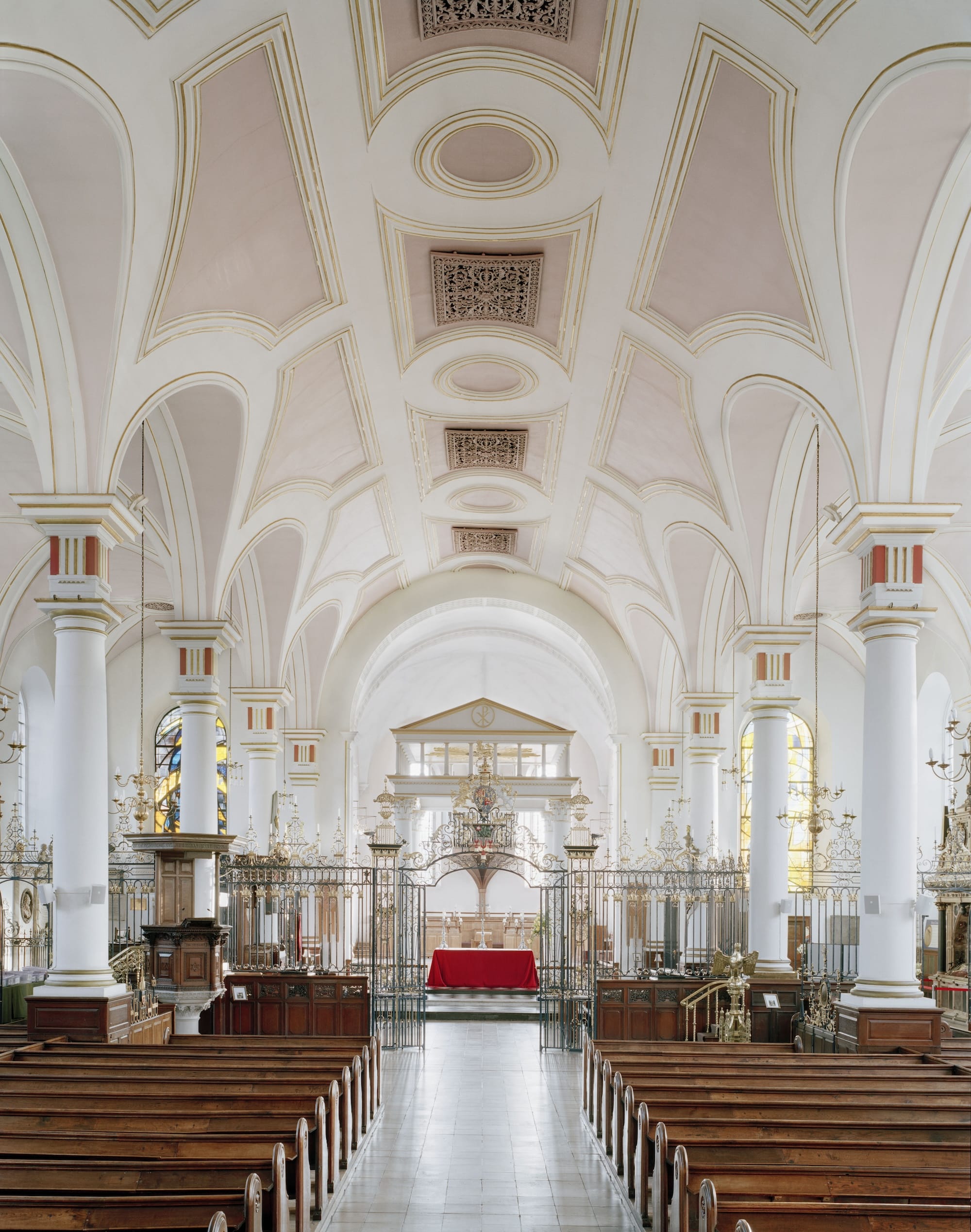 Het lichte interieur van Derby Cathedral met wit-roze gewelfde plafonds, een rood altaar en natuurlijk ochtendlicht
