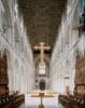 Interieur van een kathedraal met een groot hangend kruis boven het gangpad en een beschilderd houten plafond