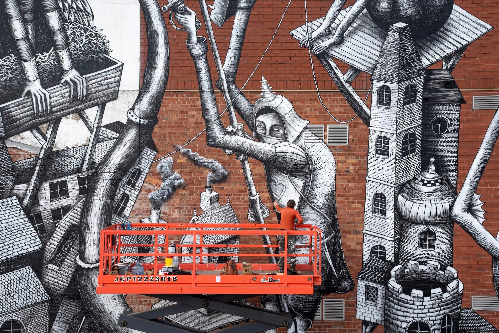Phlegm aan het werk op een hoogwerker bij een enorme zwart-witte muurschildering van een ridder en fantasiegebouwen