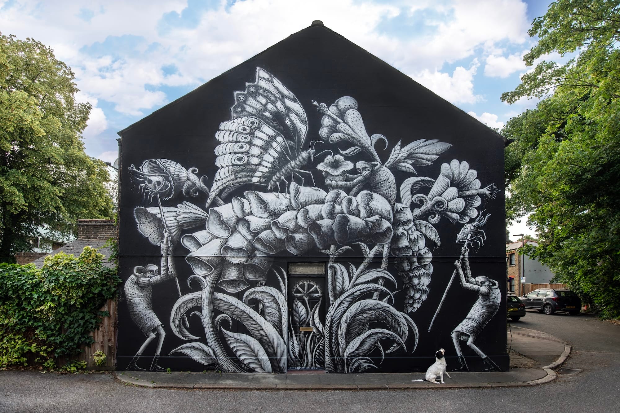 Zwart-witte muurschildering van Phlegm op een zijgevel met hybride wezens, een grote vlinder en reusachtige bloemen