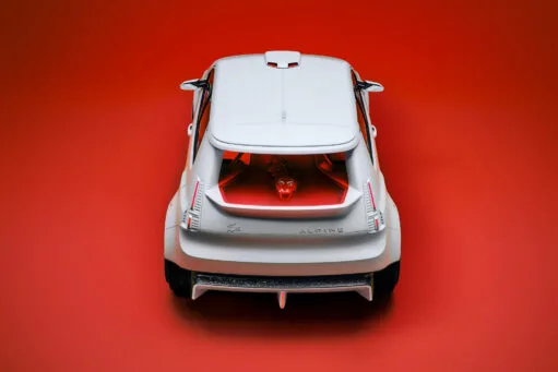 Bovenaanzicht van de achterzijde van een witte Alpine A290_β conceptauto tegen een felrode achtergrond