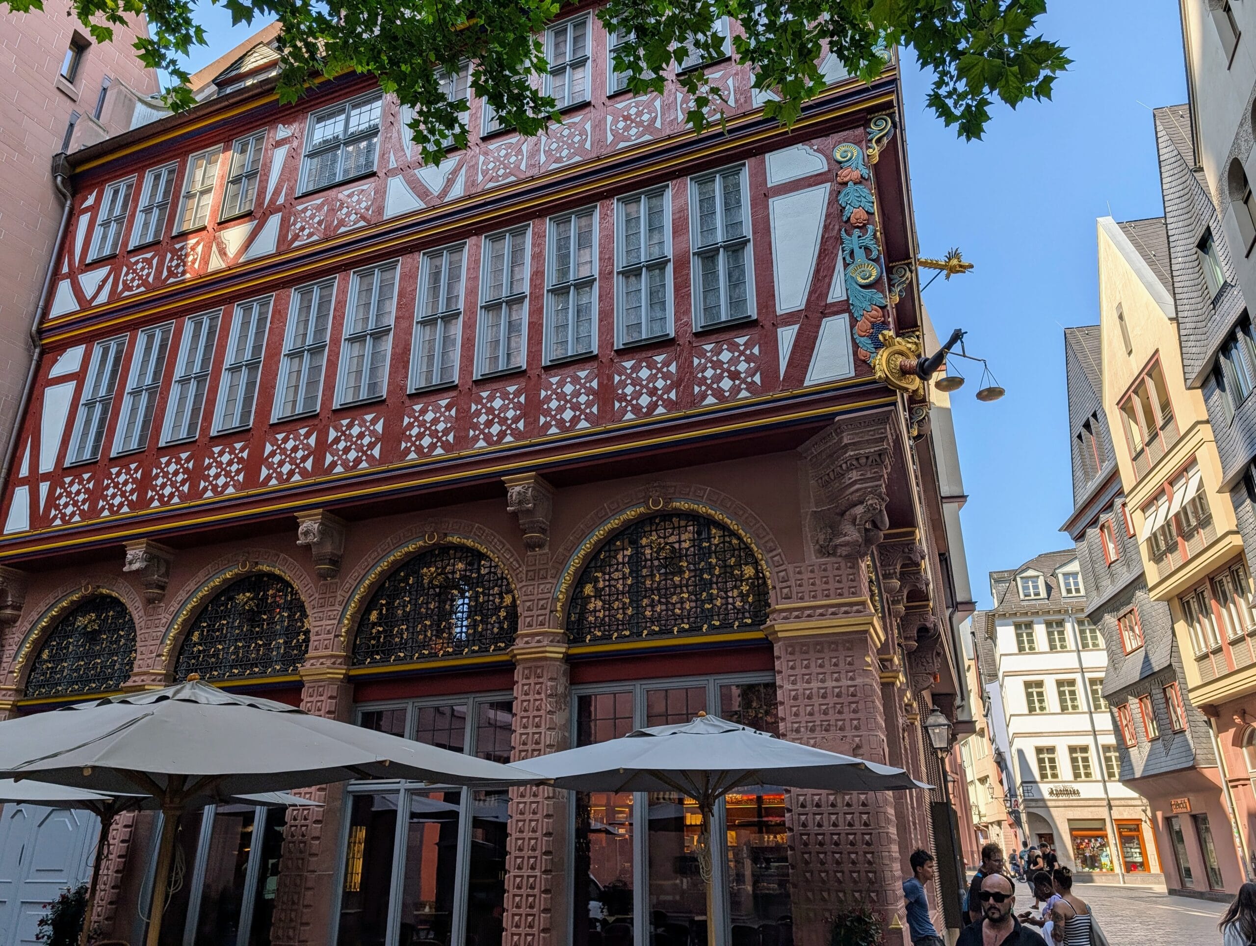 Het rijk versierde vakwerkhuis Haus zur Goldenen Waage in de Altstadt van Frankfurt met een terras op de voorgrond
