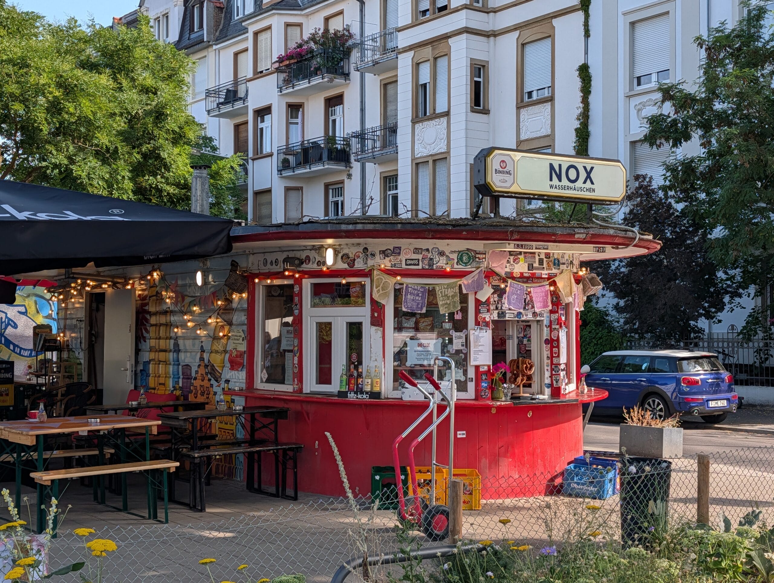 Het rode Wasserhäuschen Nox in de wijk Sachsenhausen met een terras en een uithangbord op het dak