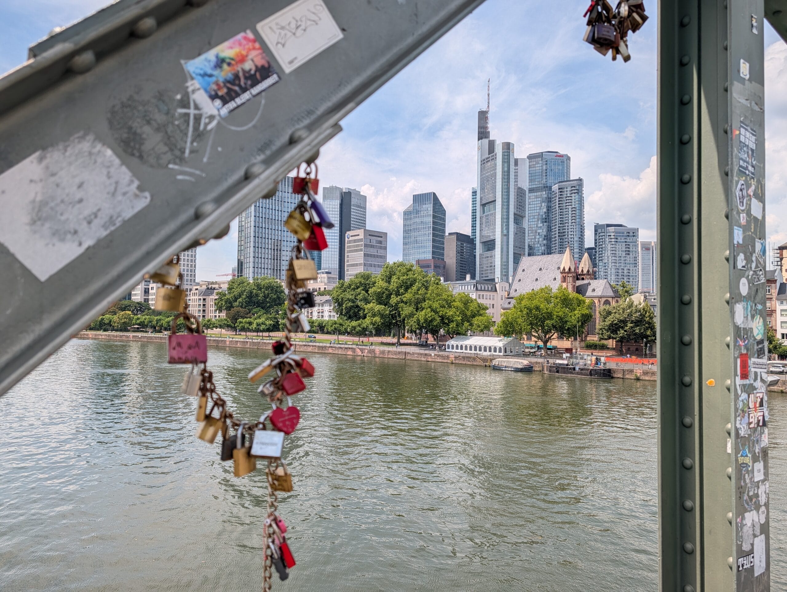 Uitzicht op de skyline van Frankfurt met wolkenkrabbers en de rivier de Main vanaf de Eiserner Steg met liefdesslotjes