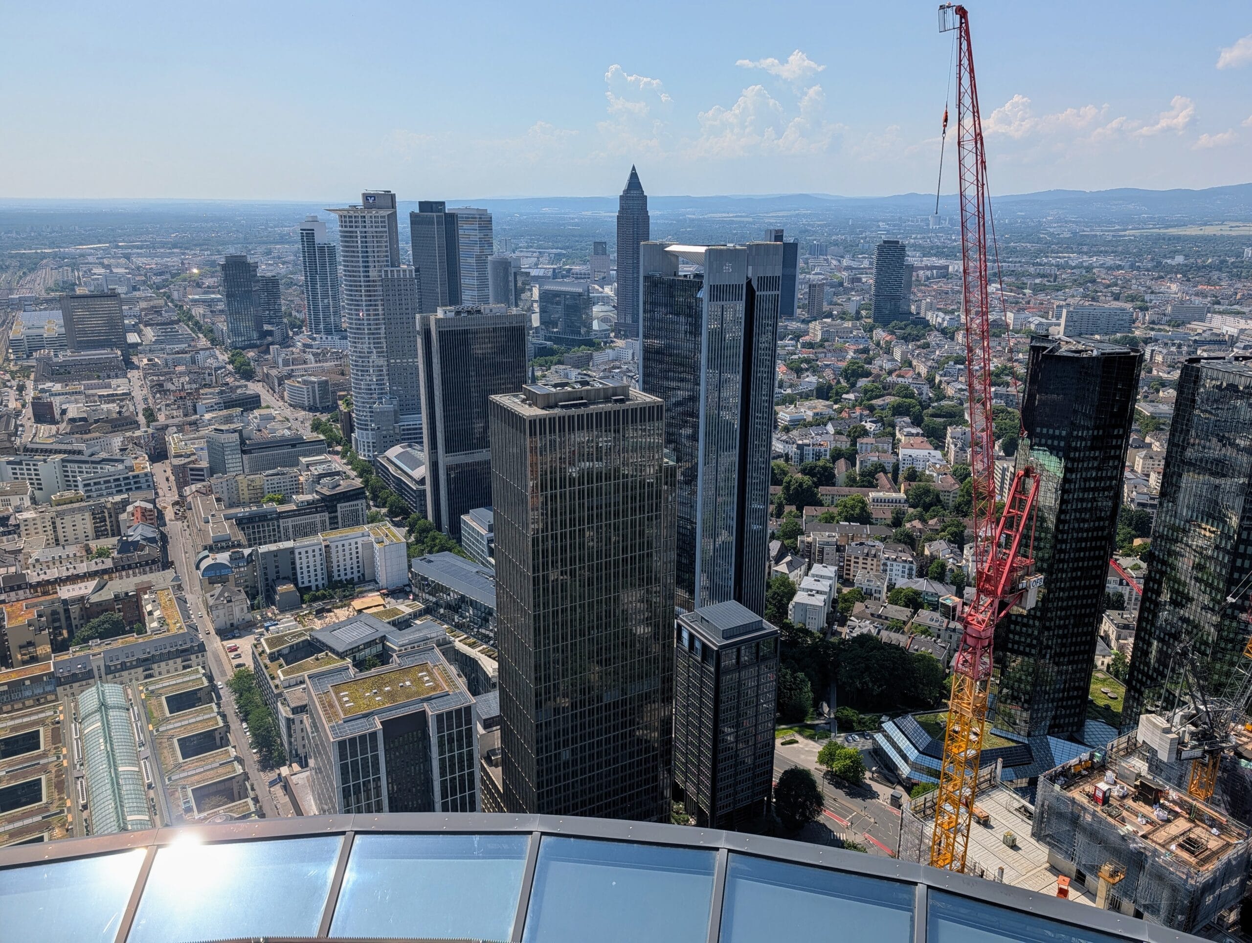 Uitzicht vanaf een hoog punt op de skyline van Frankfurt met talrijke wolkenkrabbers en een grote rode bouwkraan