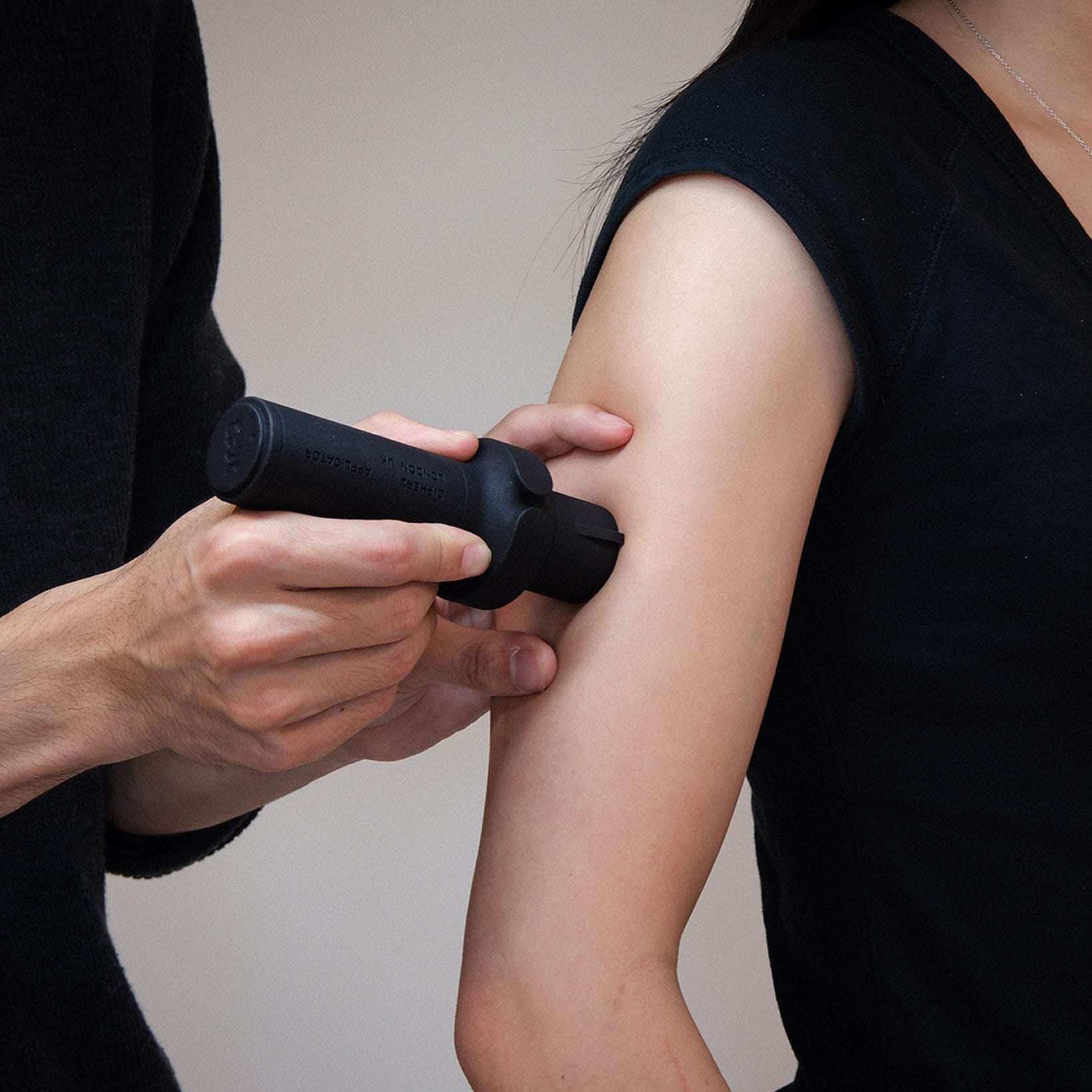 De CipherX-applicator wordt tegen de bovenarm van een persoon gedrukt om een pijnloze microdot tattoo aan te brengen