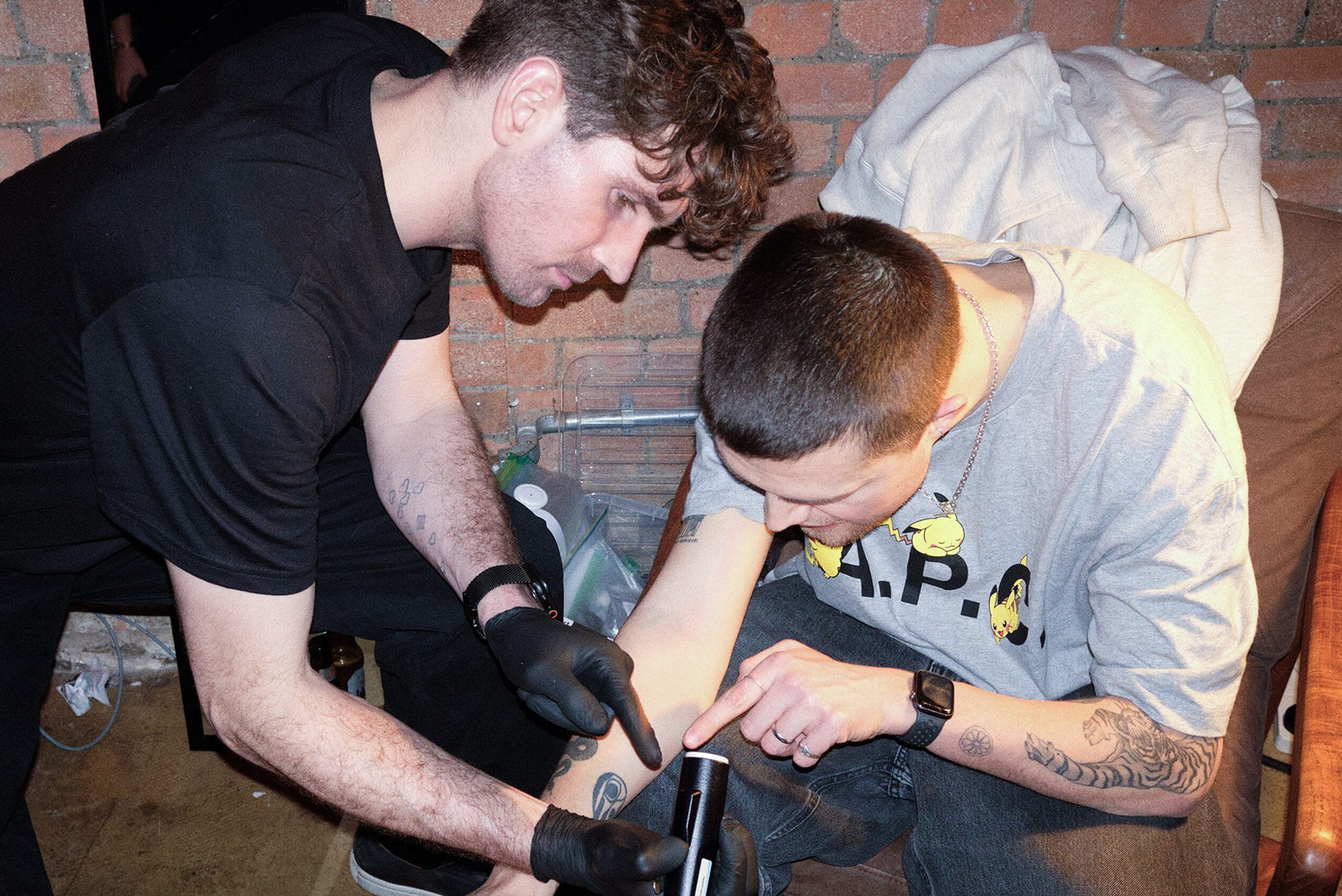 Twee mannen bekijken een kleine tatoeage op een onderarm die is aangebracht met de CipherX applicator