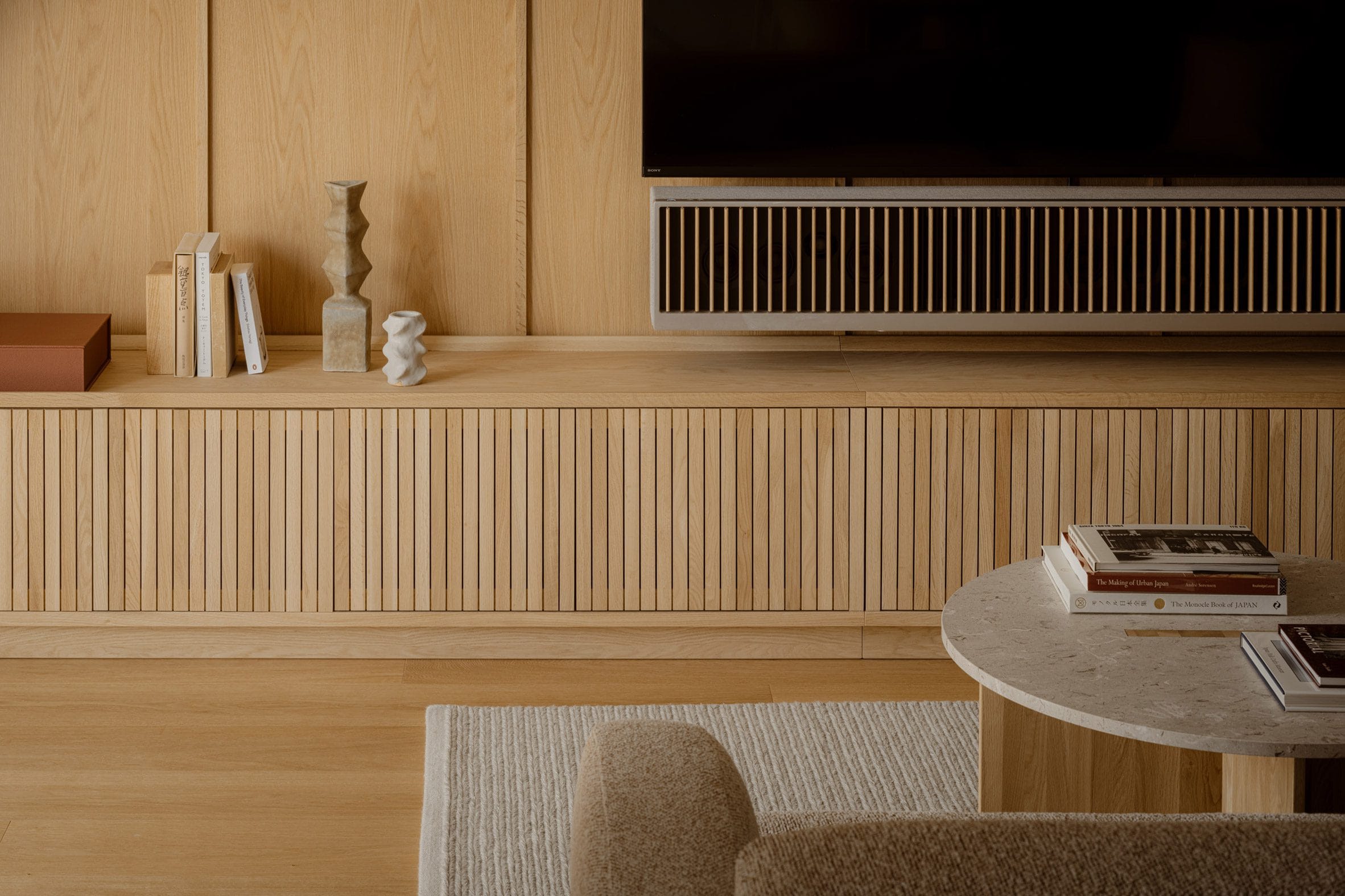 Modern Japandi interieur met een eikenhouten tv-meubel, houten wandpanelen en een marmeren salontafel