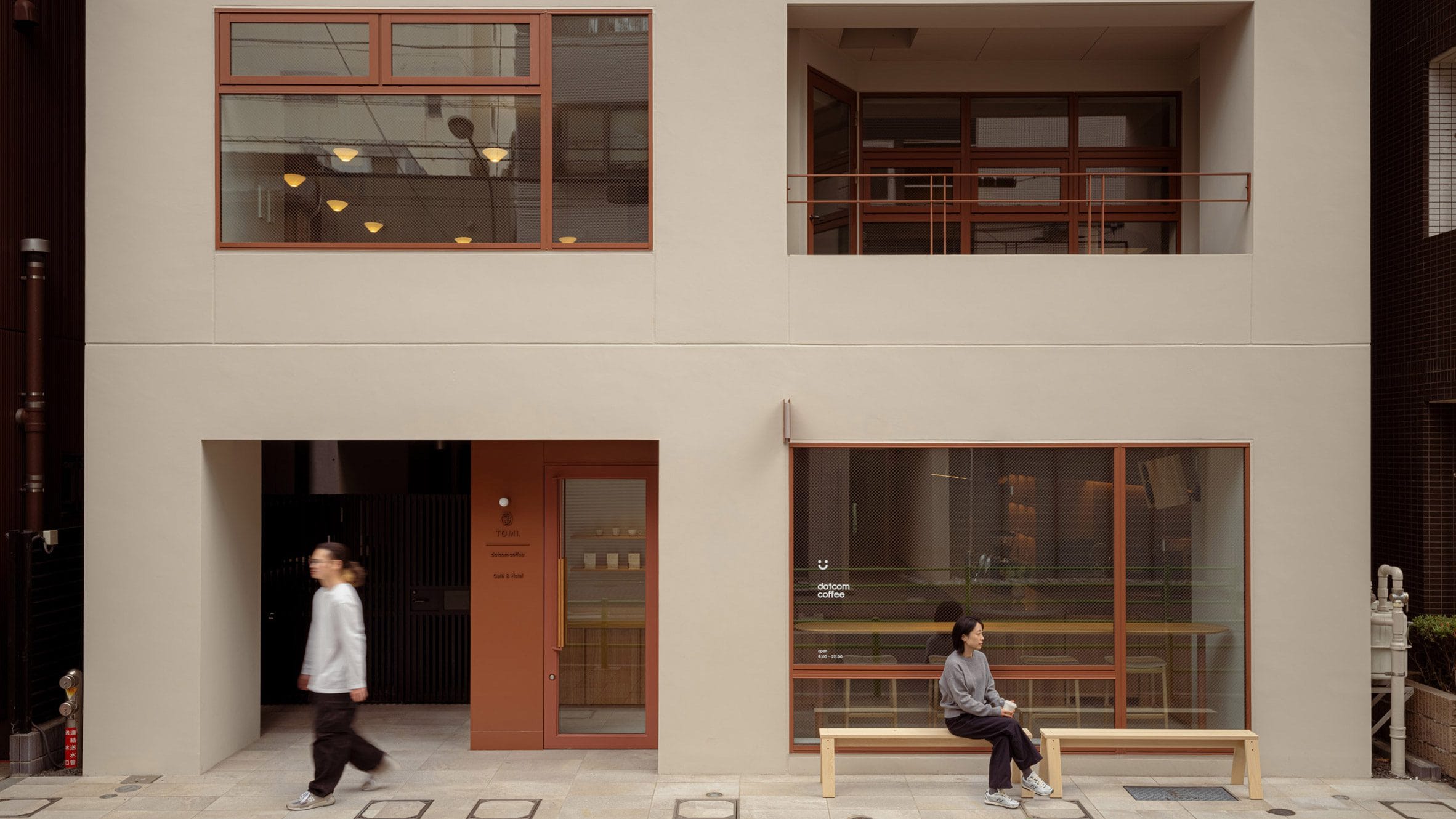 Buitenaanzicht van Tomi Hotel Ginza met een minimalistische beige gevel, bruine kozijnen en mensen voor de ingang