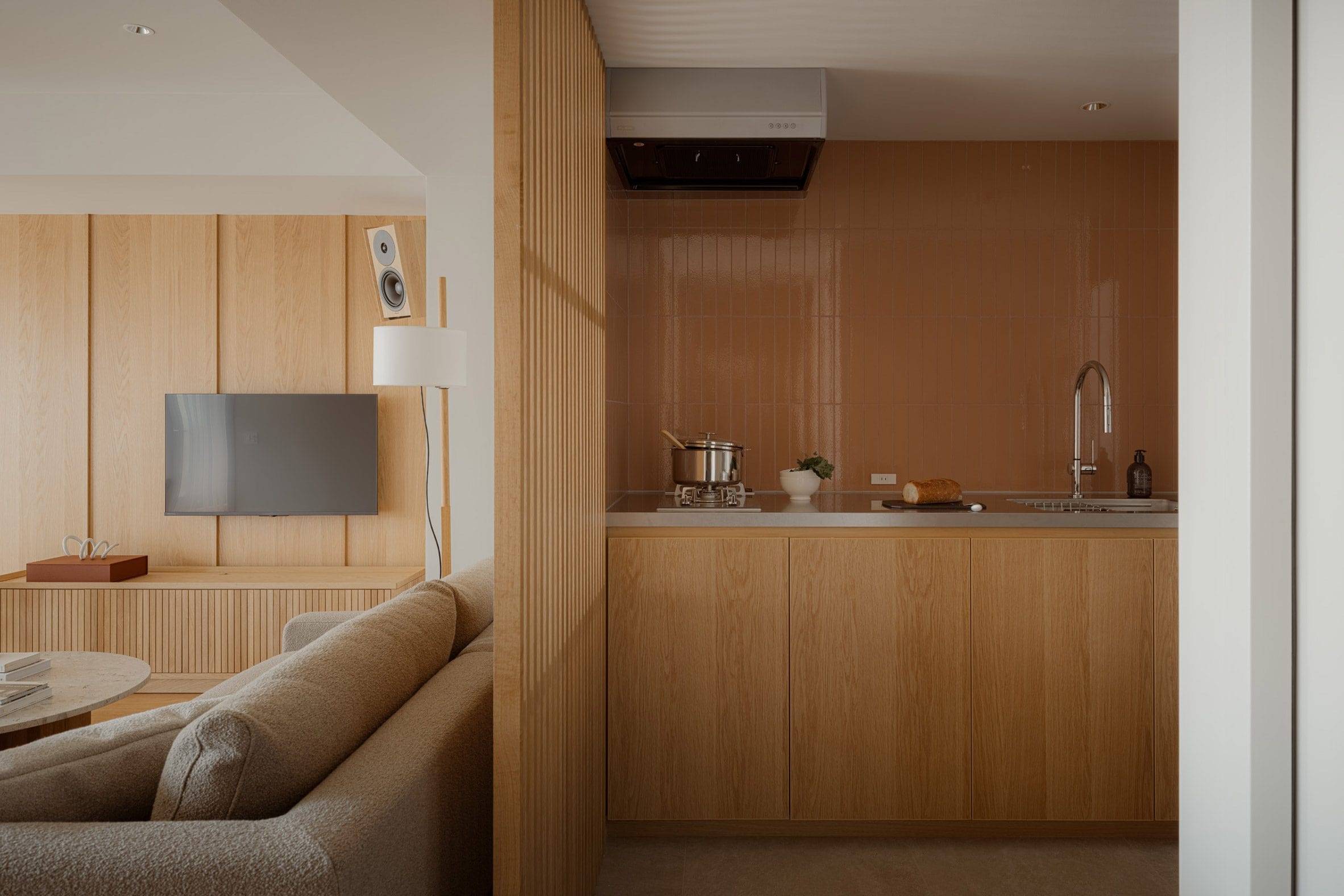 Modern interieur met een houten keukenblok en een woonkamer gescheiden door een lattenwand