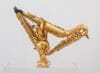 Een sculptuur van drie gouden saxofoons die in elkaar zijn gevlochten tot een abstracte, driehoekige vorm op een sokkel