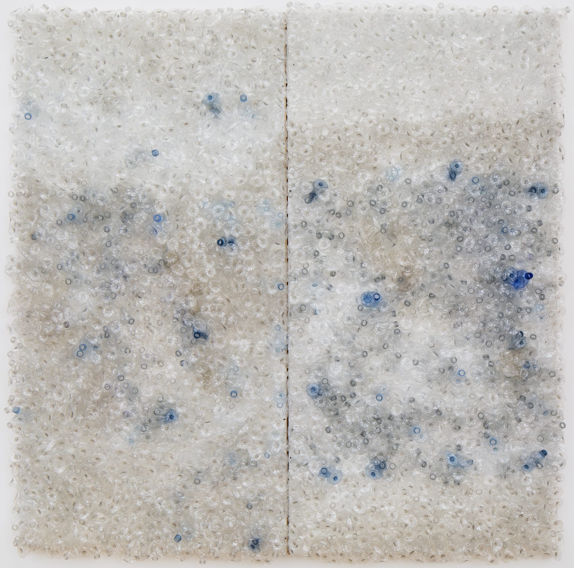 Een abstract kunstwerk bestaande uit duizenden dicht op elkaar gepakte transparante en blauwe plastic flessenhalzen