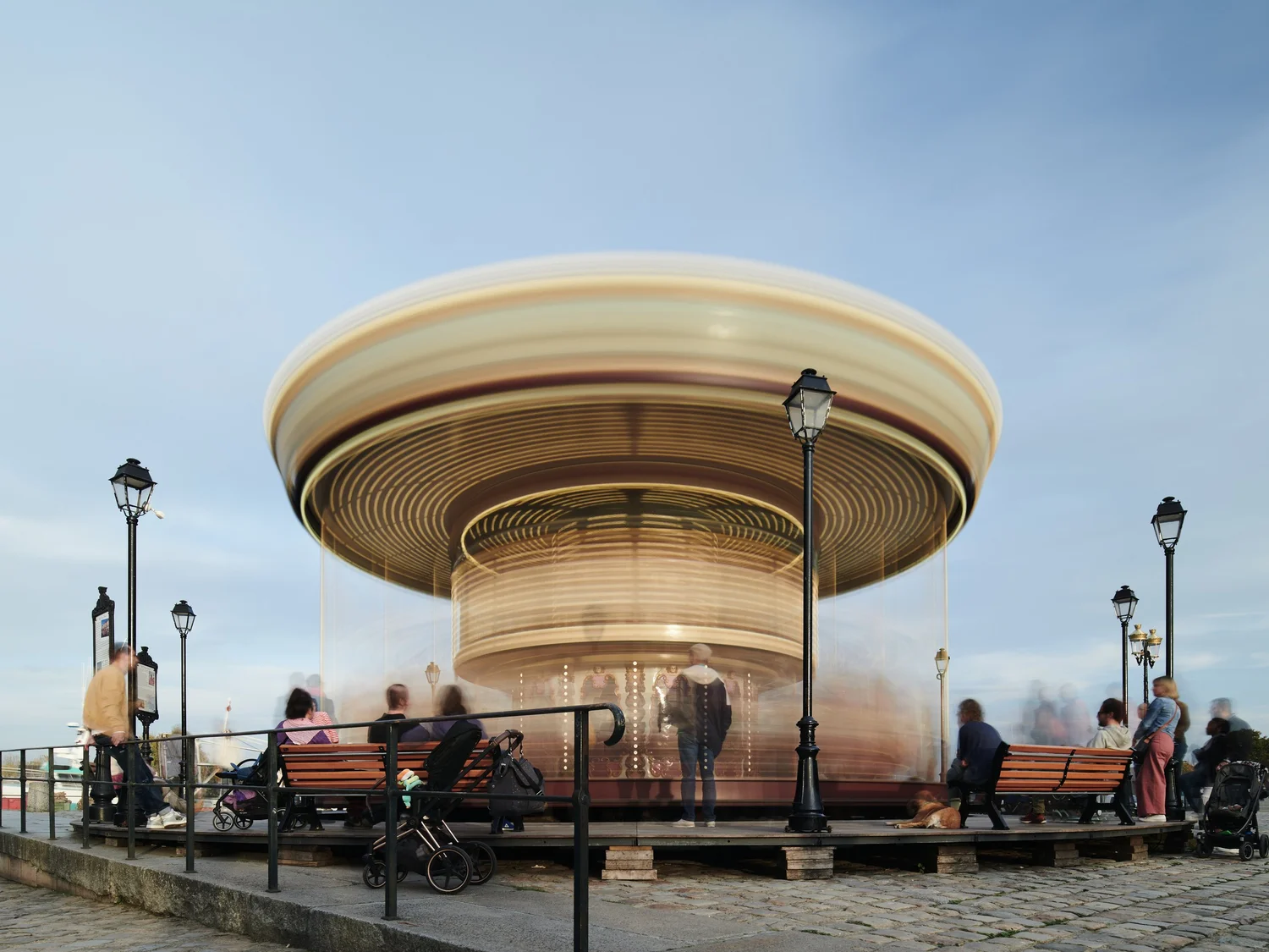 Ronddraaiende carrousel met bewegingsonscherpte op een plein in Honfleur, omringd door toeschouwers op bankjes