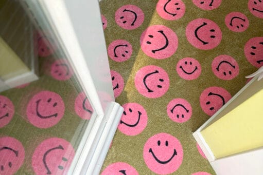 Deurmat met een patroon van roze smileys bij een deuropening