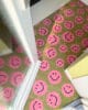 Deurmat met een patroon van roze smileys bij een deuropening