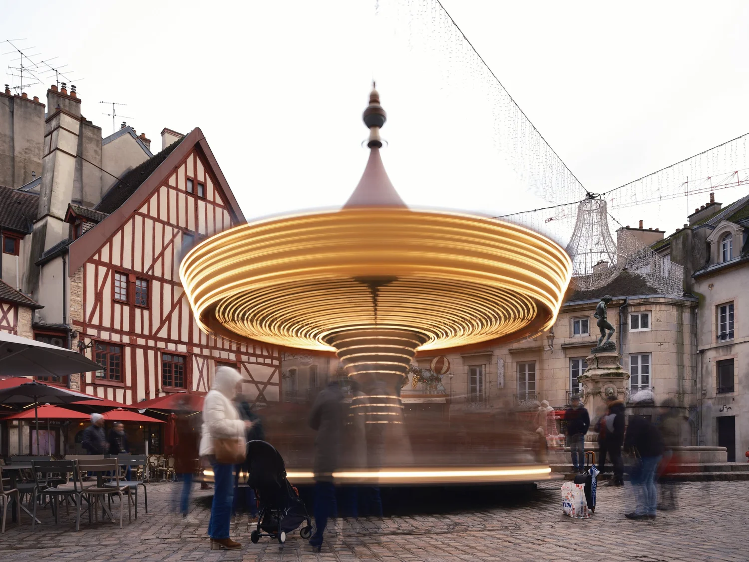 Draaiende carrousel vastgelegd met lange sluitertijd op een plein met vakwerkhuizen in Dijon