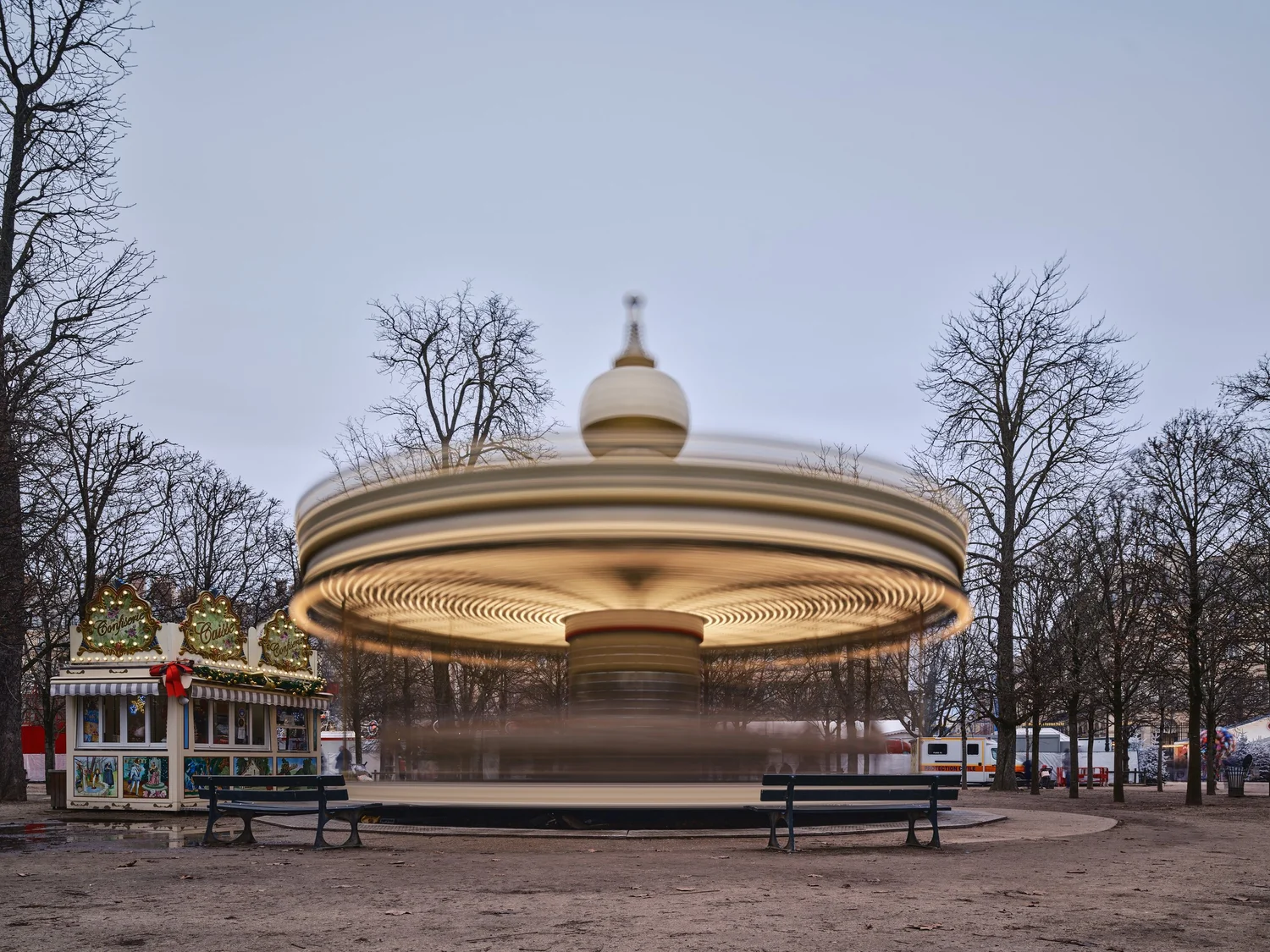Draaiende carrousel vervaagd tot een lichtschijf door lange sluitertijd in een park met kale bomen