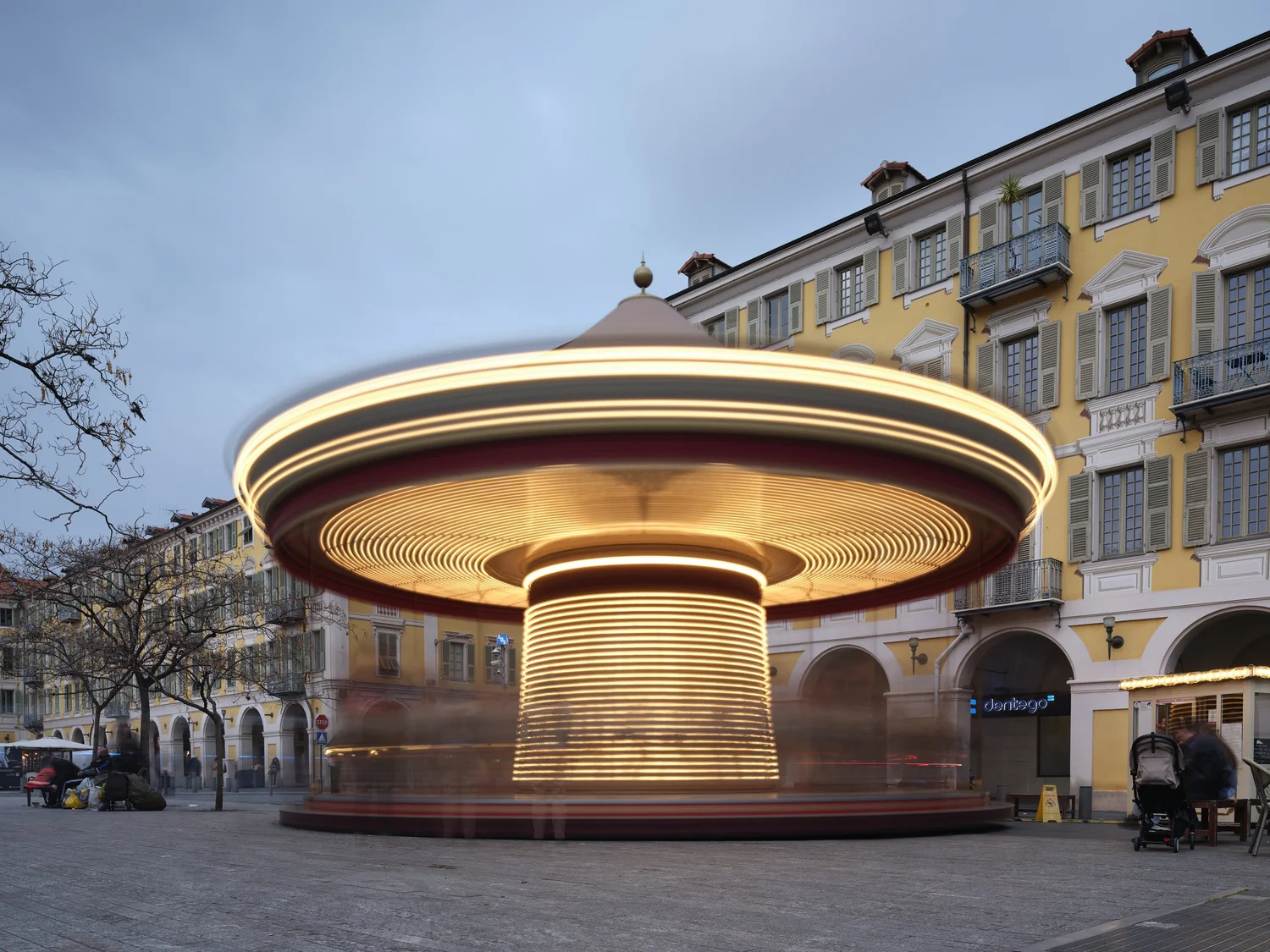Draaiende, verlichte carrousel met lange sluitertijd die vloeiende banen van licht vormt op een stadsplein