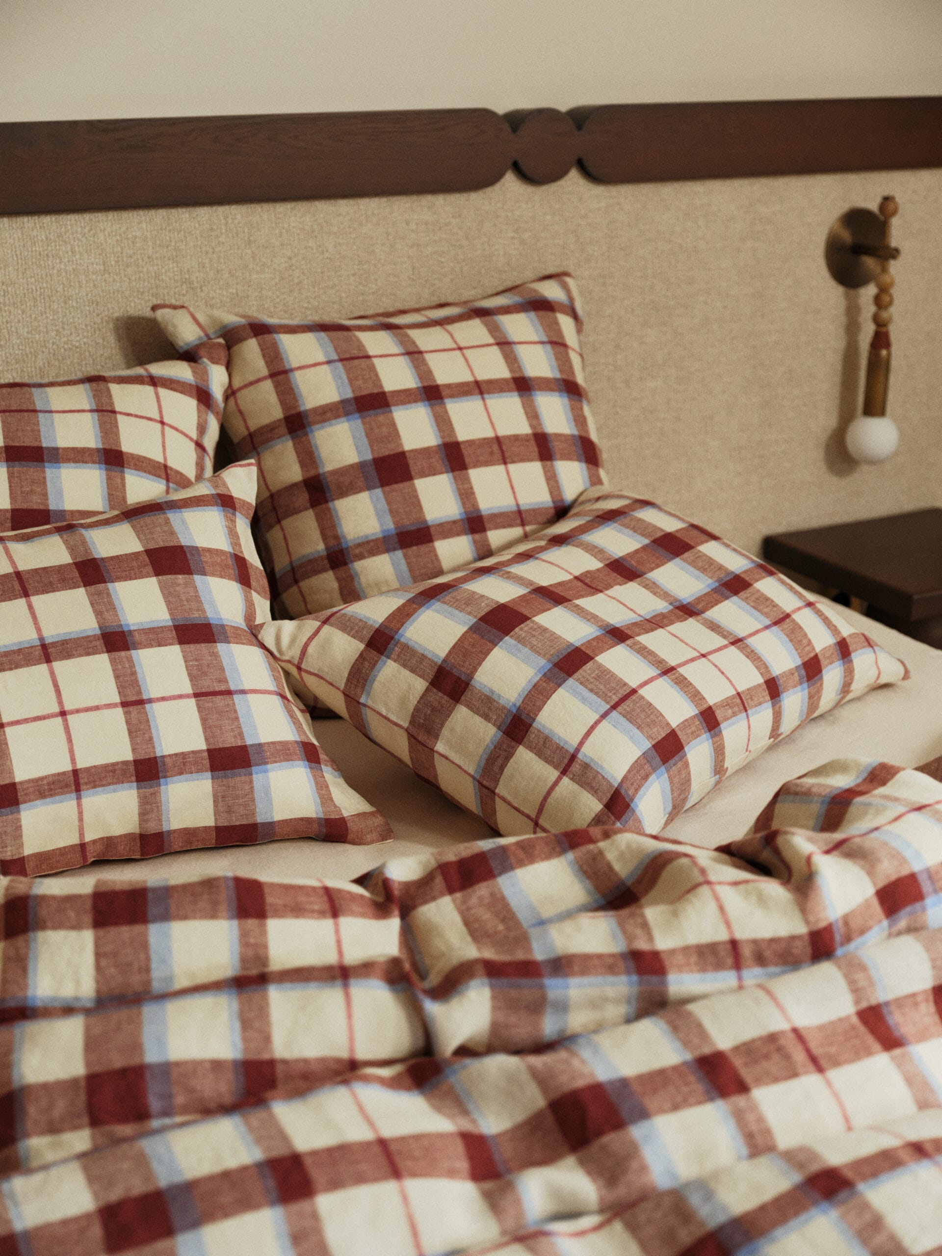 Beddengoed en kussens met een rood, blauw en beige ruitpatroon op een bed, uit de Essentials collectie van Bonsoirs
