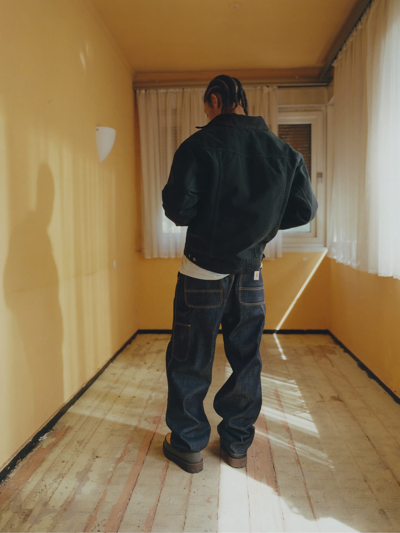 Man op de rug gezien in een donker OG Trucker Jacket en een ruimvallende denim Double Knee Pant met contraststiksels