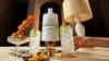 Een witte fles Hendrick's Gin omringd door twee glazen gin-tonic met komkommer en een schaal met sinaasappels