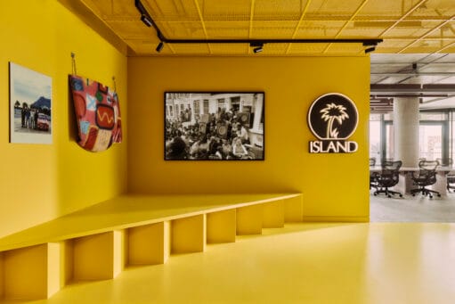 Een felgele kantoorruimte met het Island Records-logo en zwart-witfoto's aan de muur