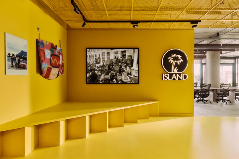 Een felgele kantoorruimte met het Island Records-logo en zwart-witfoto's aan de muur