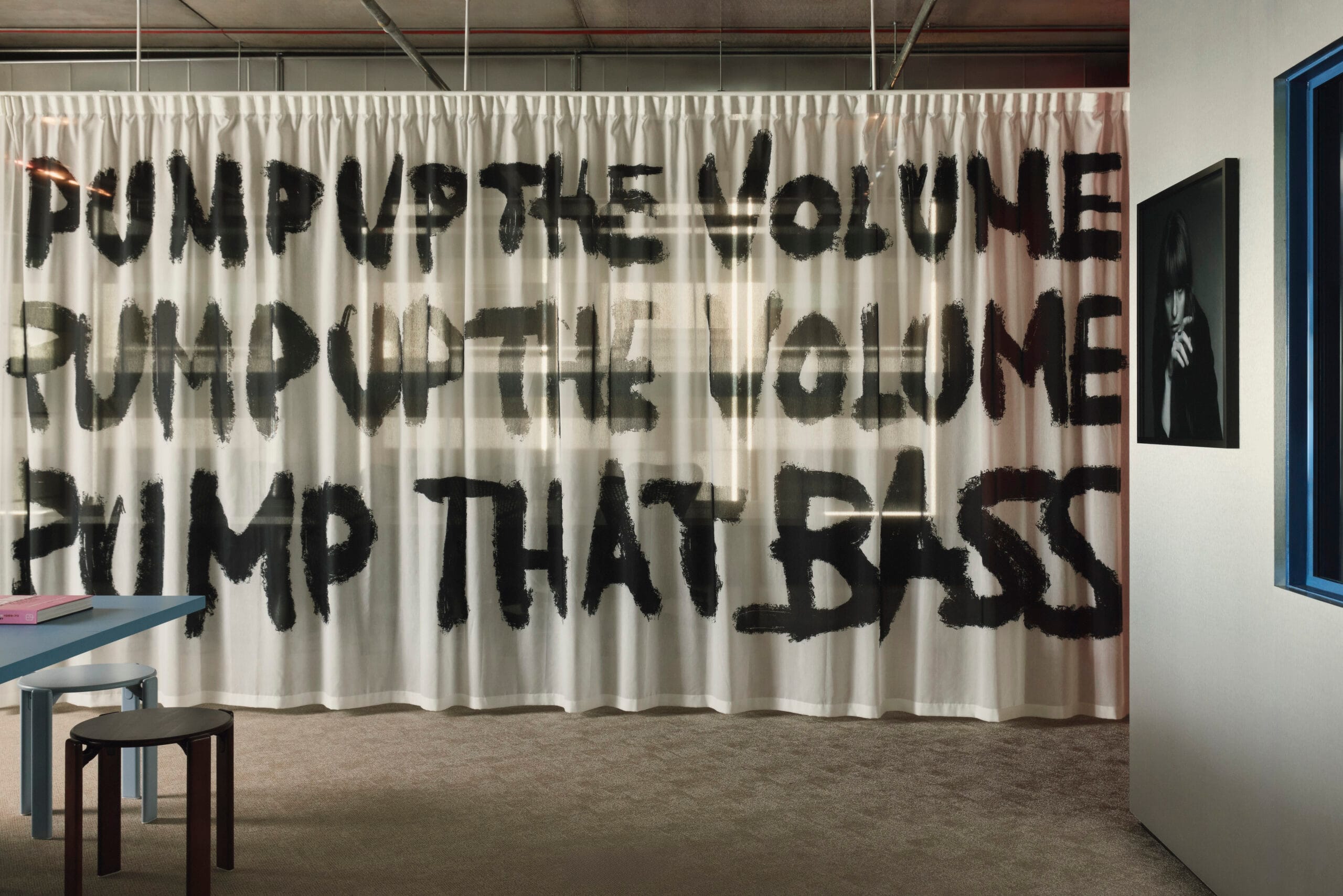 Een gordijn met de tekst Pump up the volume, Pump up the volume, Pump that bass in zwarte letters in het kantoor van EMI
