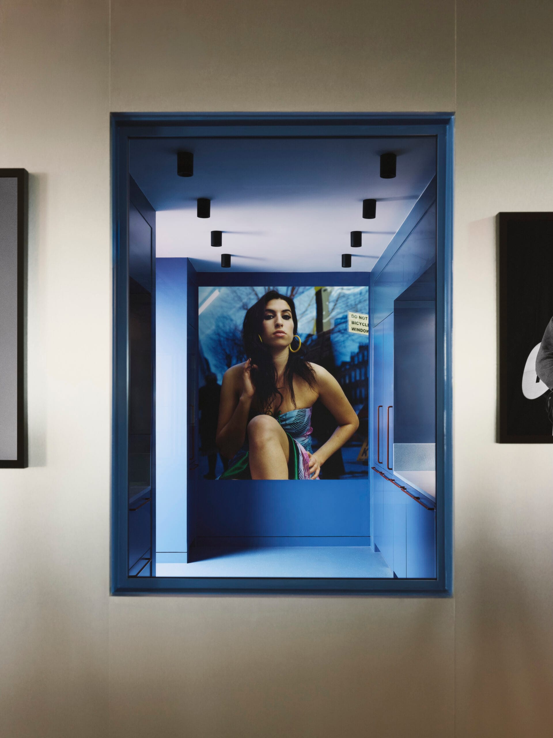 Een blauw interieur van het EMI-kantoor met een grote foto van Amy Winehouse aan het einde van een gang
