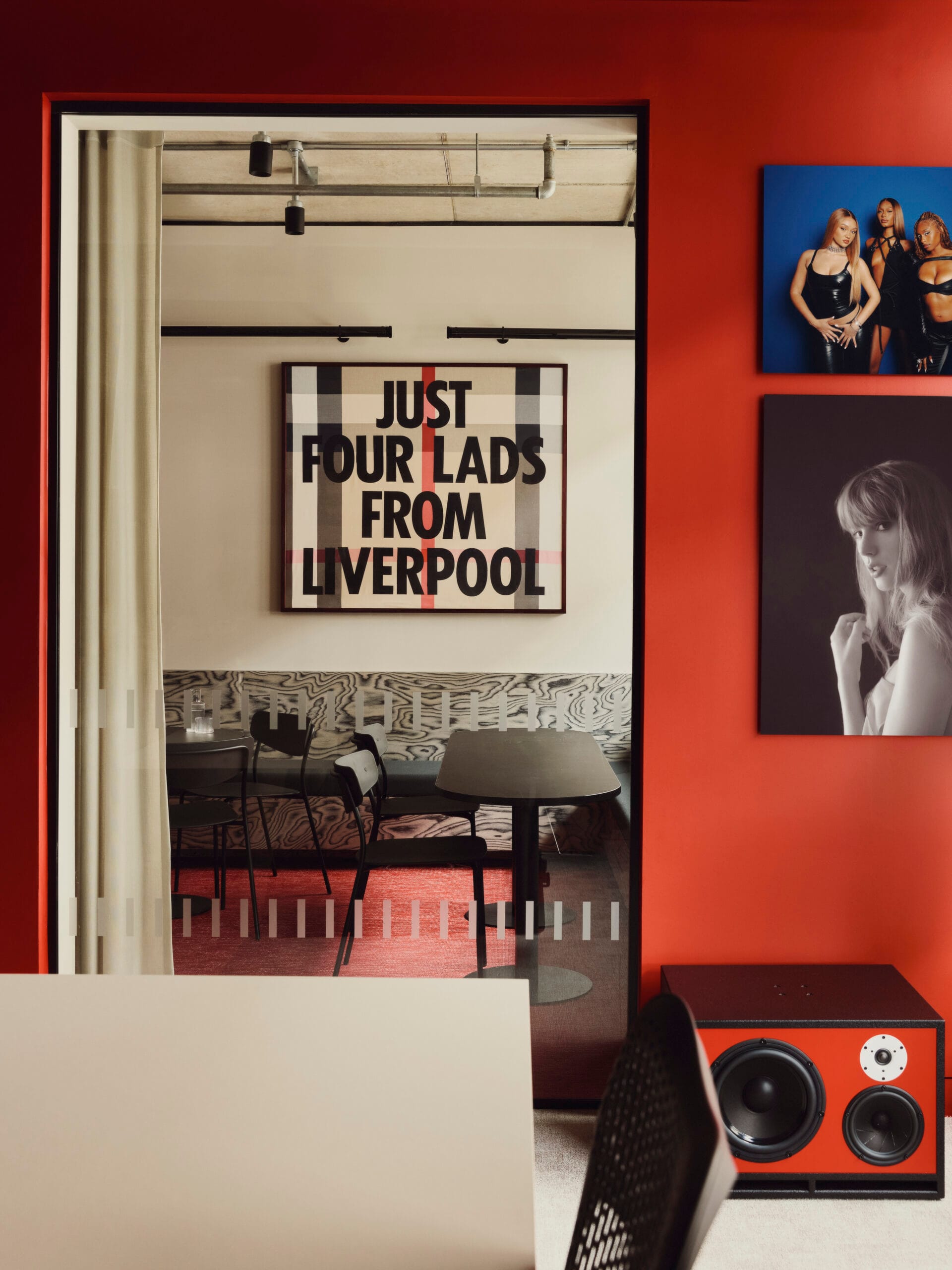 Interieur van het EMI-kantoor met een rode wand vol kunstwerken van artiesten en een bord met de tekst Just Four Lads From Liverpool